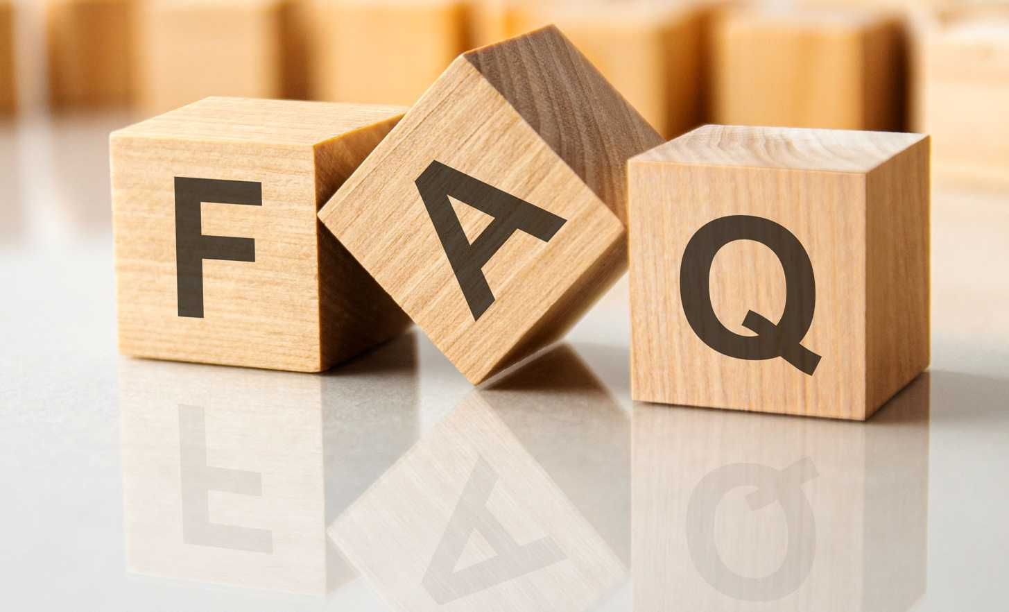 Three wooden blocks arranged on a reflective white surface, each displaying a letter to spell