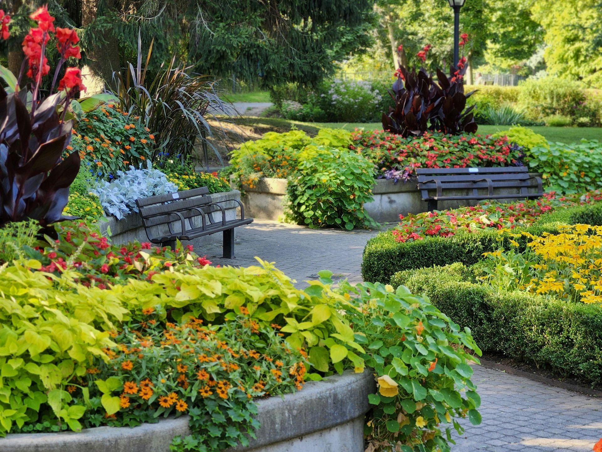 Colorful garden path with flower beds, lush greenery, and stone planters in a landscaped park