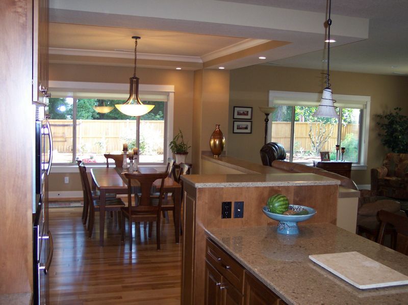 An open-concept kitchen and dining area with hardwood floors, wooden cabinets, and hanging pendant lights.