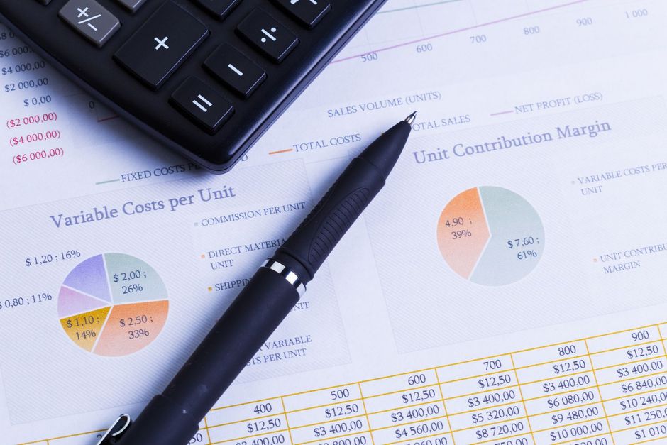 Calculator and pen on financial reports with charts and tables.