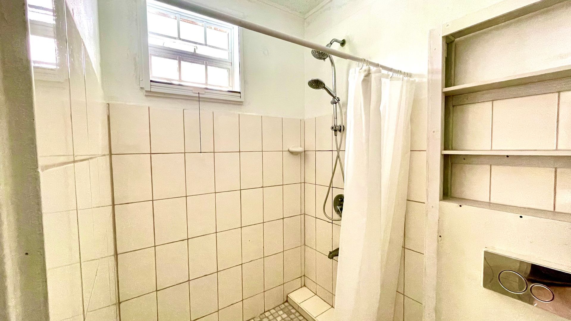 A bathroom with a shower curtain and a window.