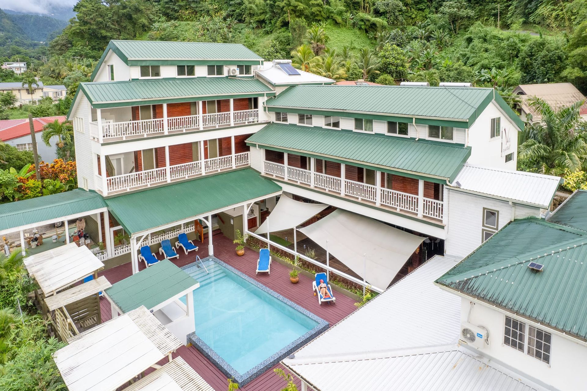 An aerial view of a hotel with a swimming pool surrounded by trees.