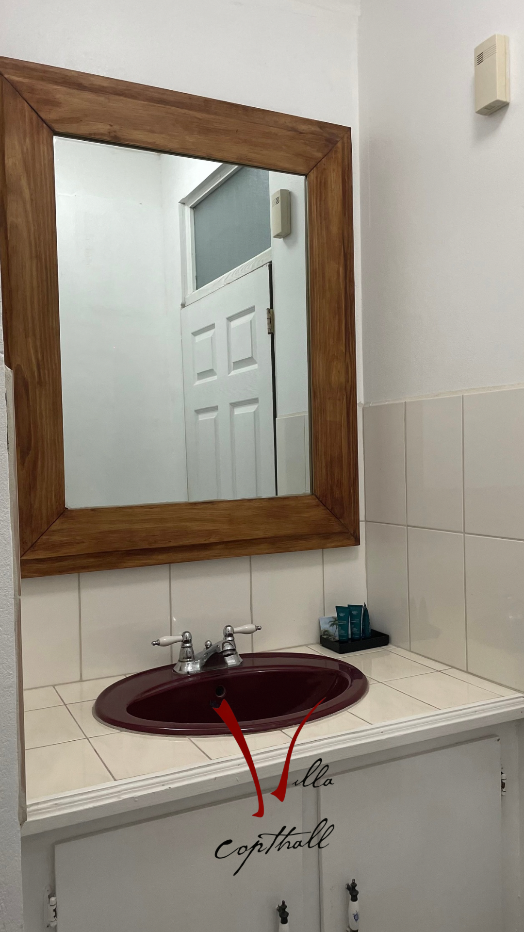A bathroom sink with a wooden mirror above it