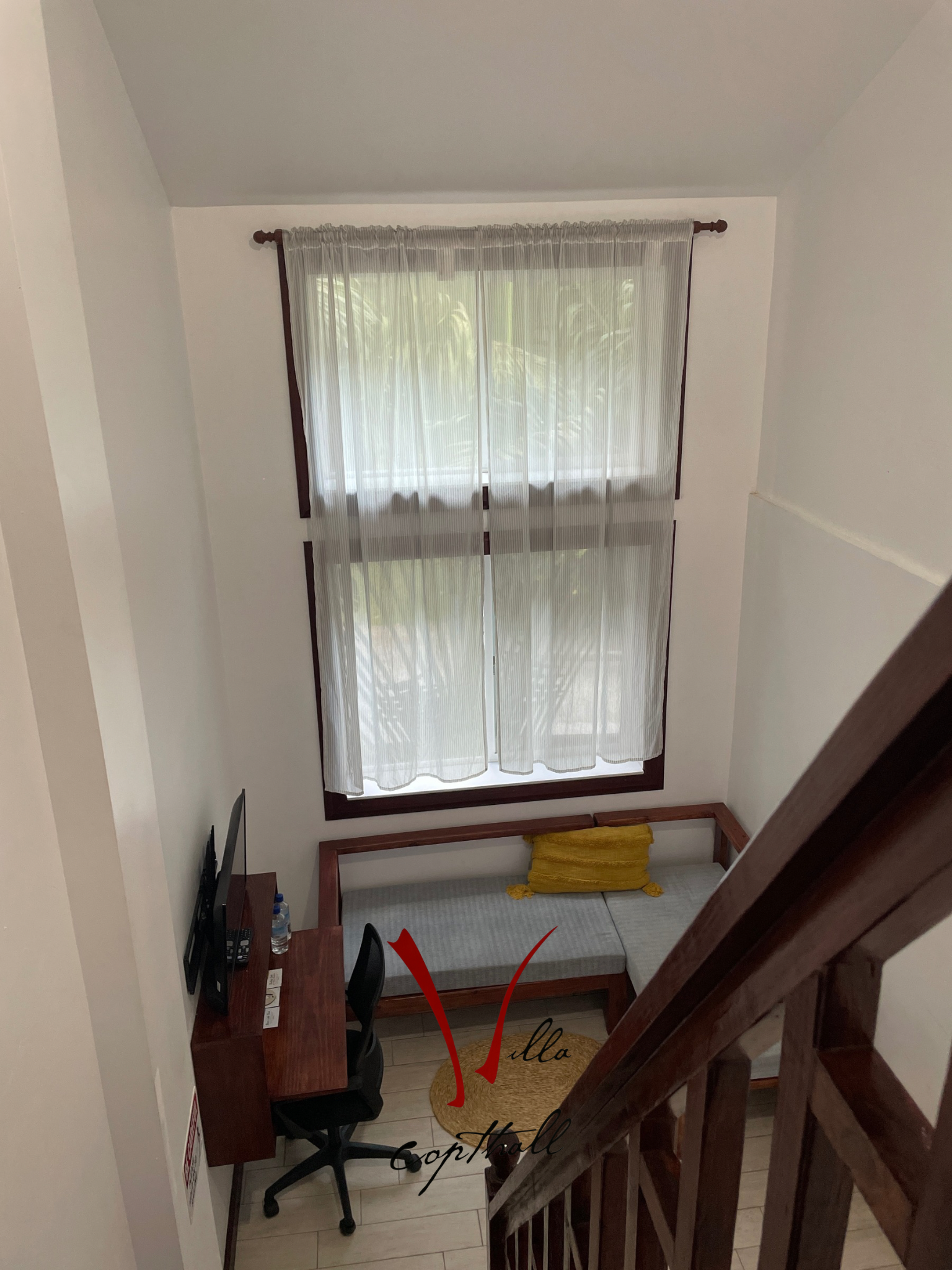 A room with a couch , desk , chair and window.
