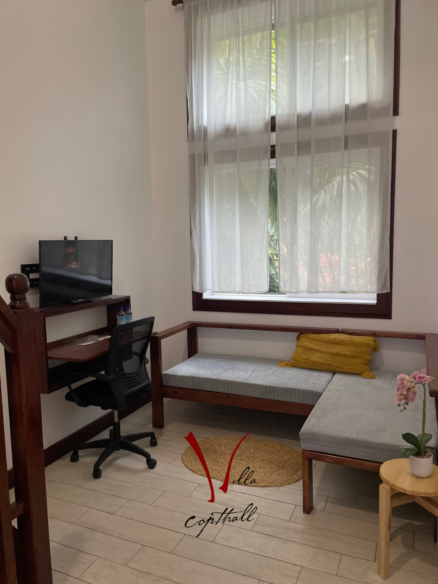 A living room with a couch , desk , chair and television.