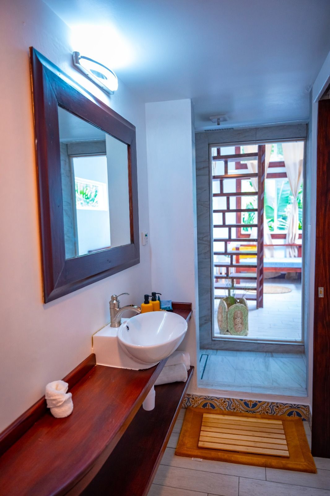 A bathroom with a sink , mirror and door leading to a balcony.