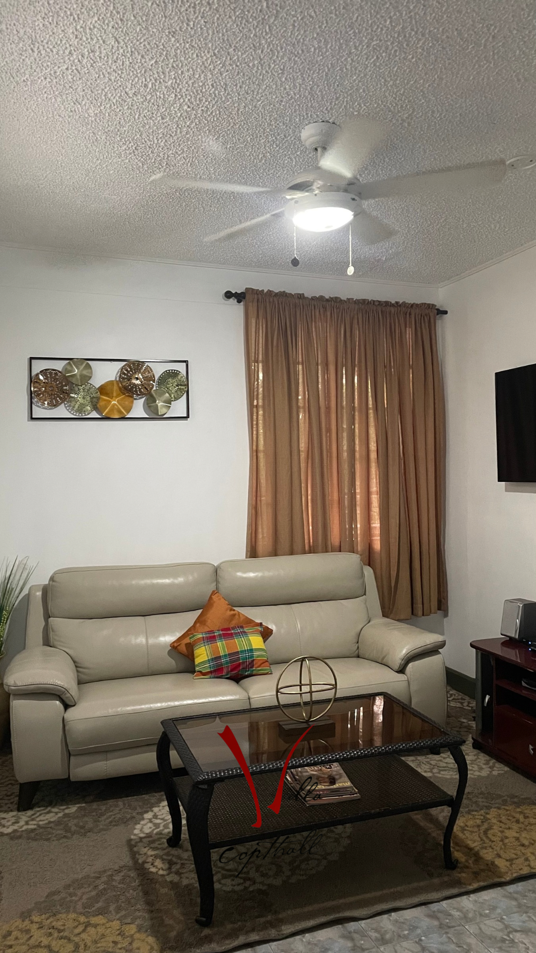 A living room with a couch , coffee table , and ceiling fan.