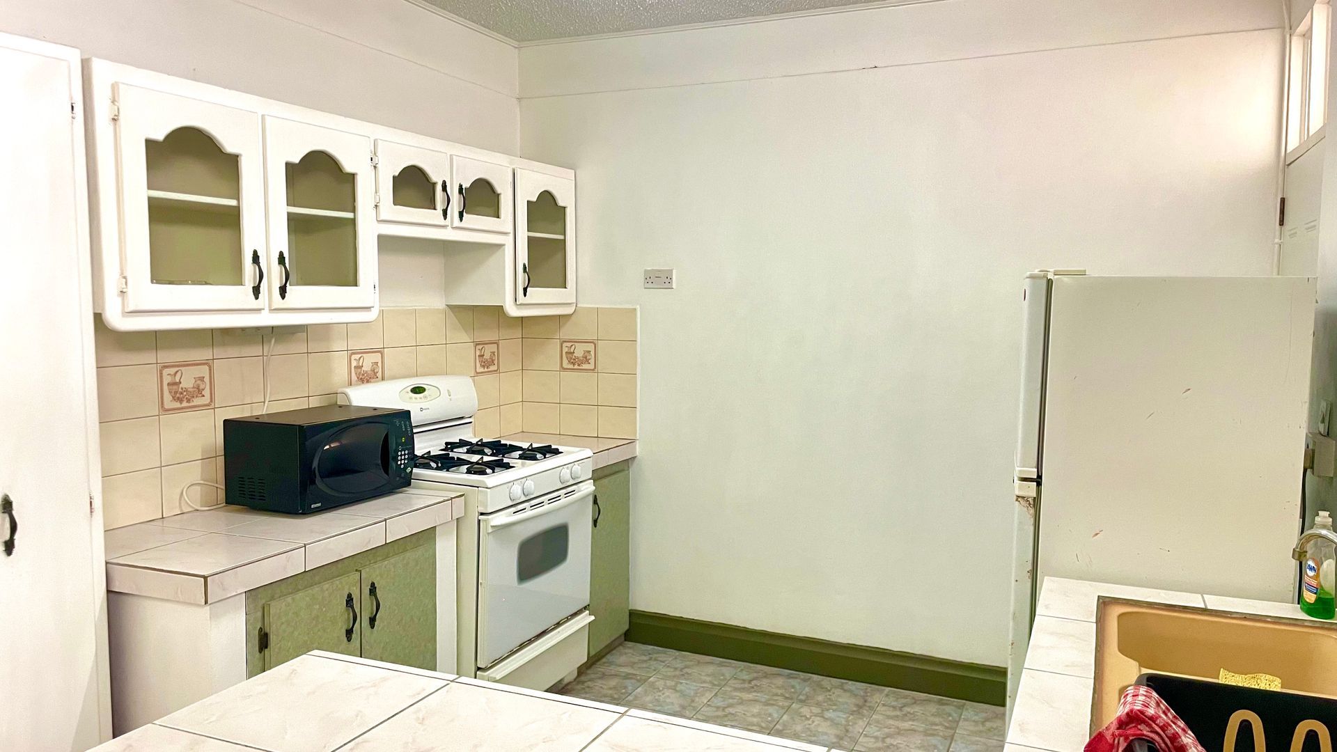 A kitchen with a stove , microwave , refrigerator and sink.