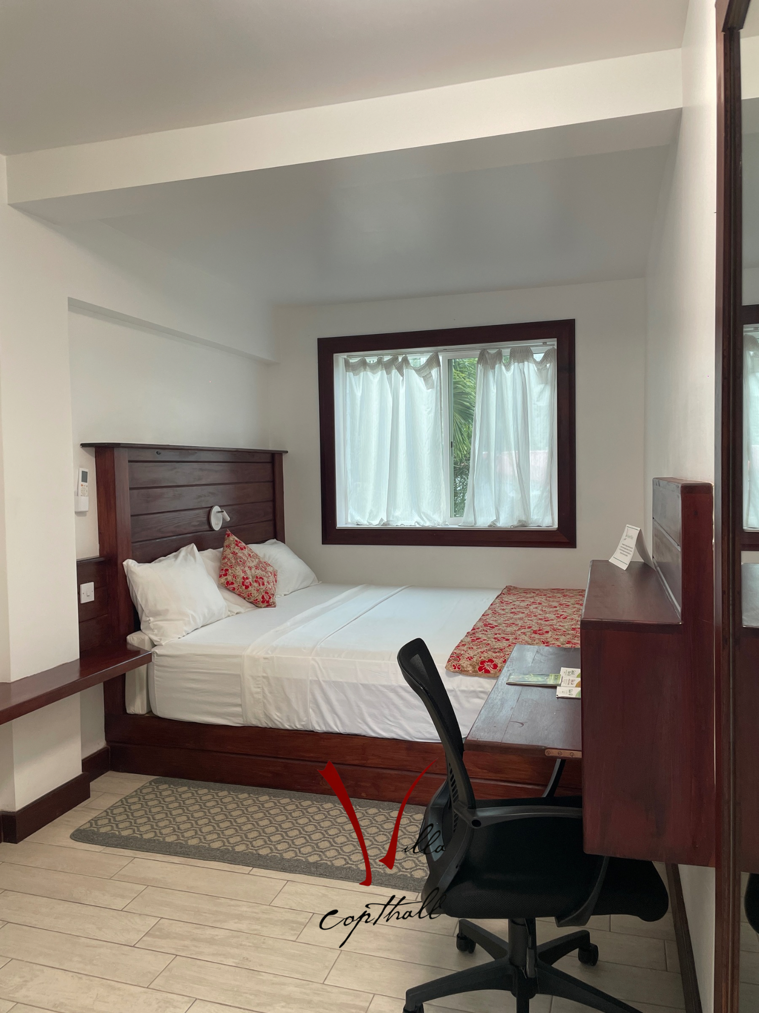 A hotel room with a bed , desk , chair and mirror.