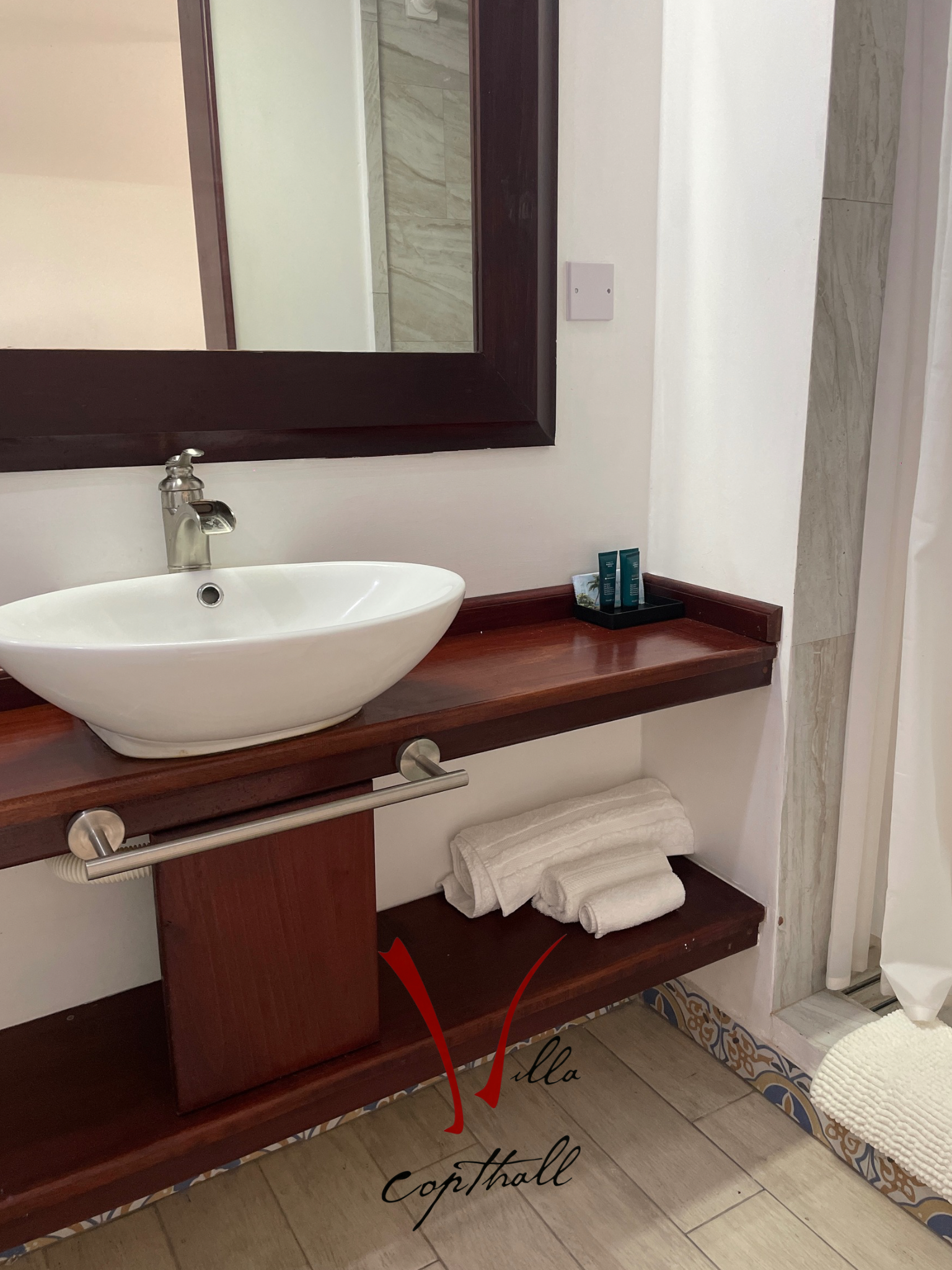 A bathroom with a sink , mirror and towels