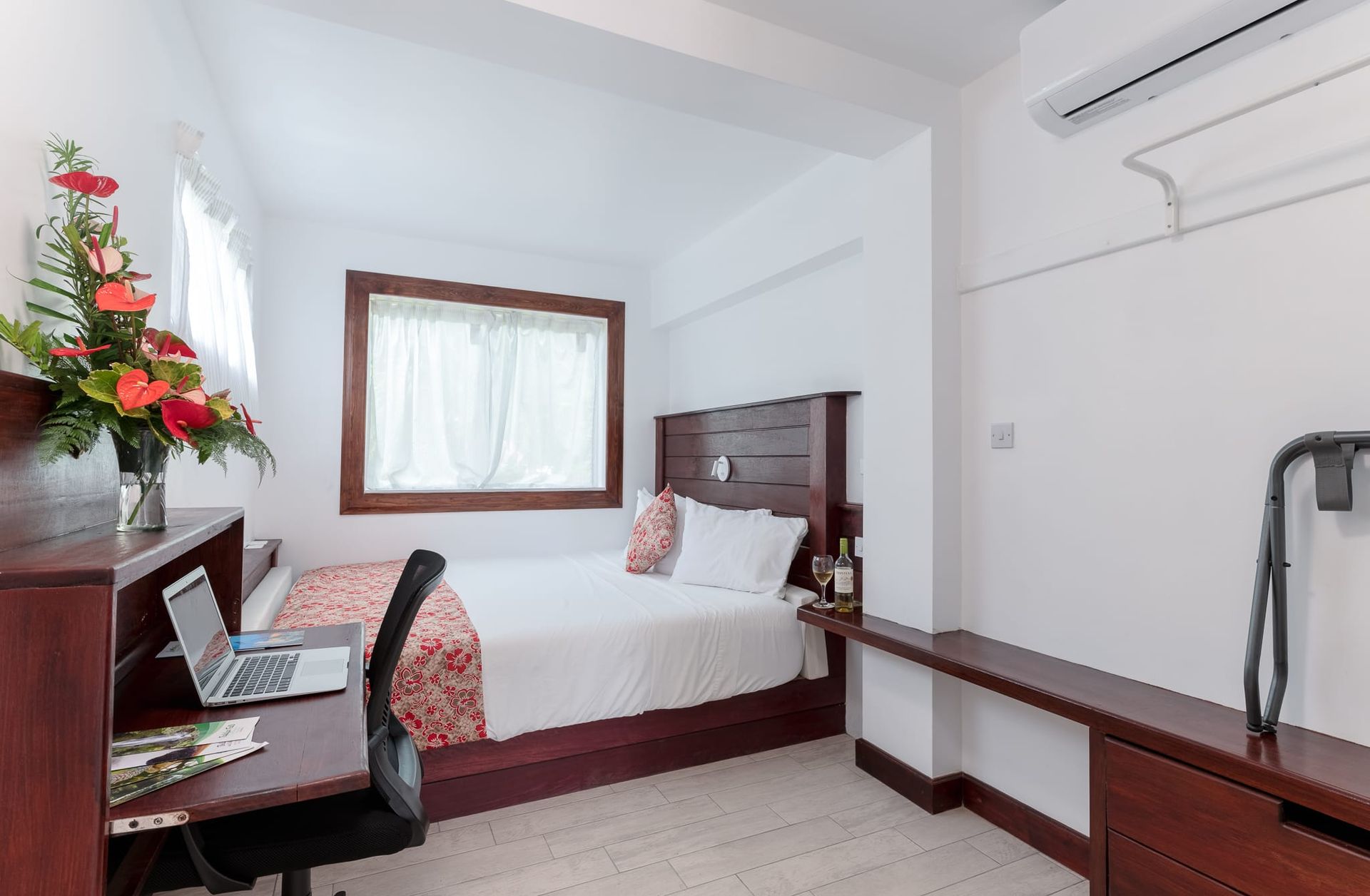 A hotel room with a bed , desk , chair and laptop.