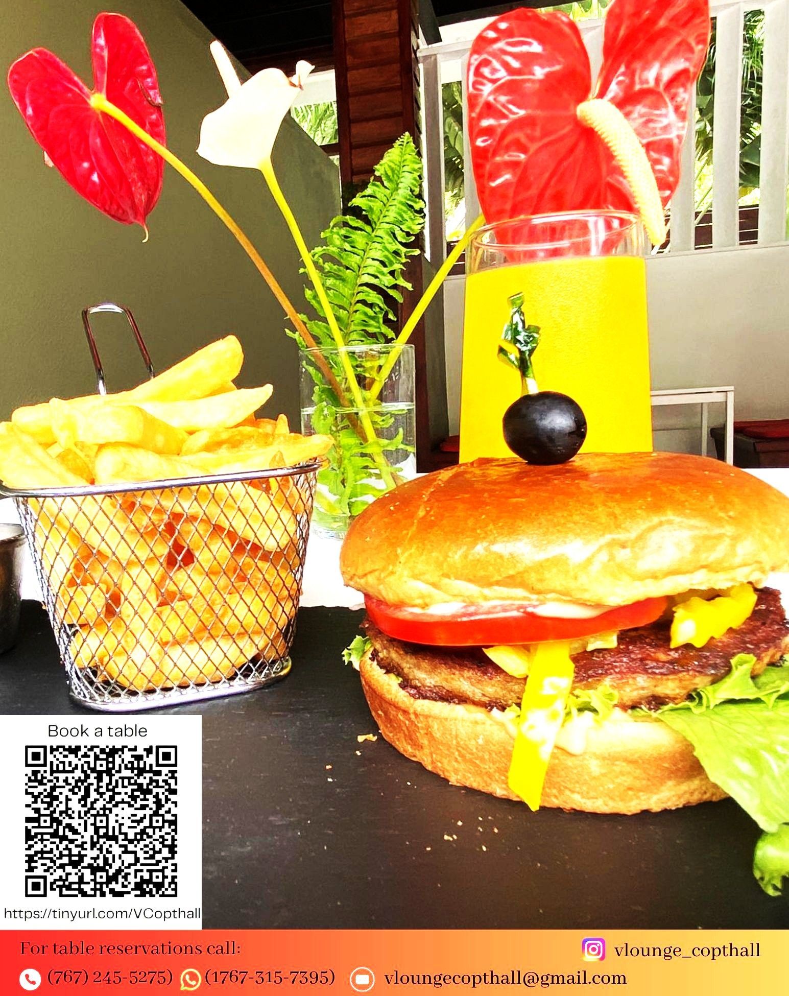 A hamburger and a basket of french fries on a table from V lounge Restaurant inside Villa copthall.