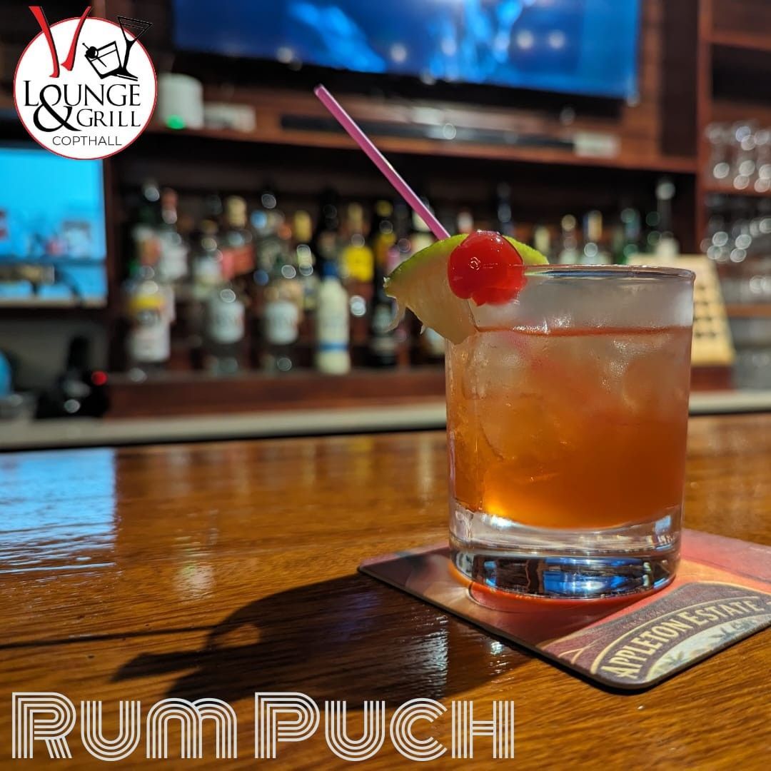 A glass of rum puchi is on a coaster on a bar at V lounge Restaurant inside Villa copthall. 