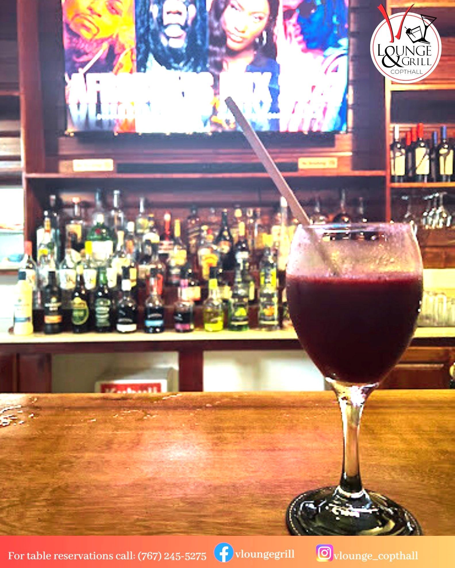 A glass of wine with a straw in it is sitting on a bar  at V lounge Restaurant inside Villa copthall. 