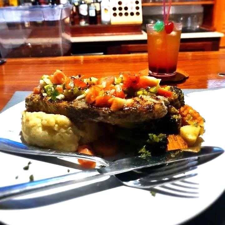 A plate of food with a drink in the background from V lounge Restaurant inside Villa copthall.