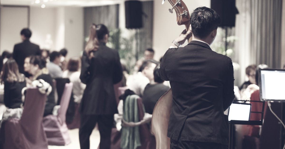 A man in a suit is playing a double bass at a wedding reception.