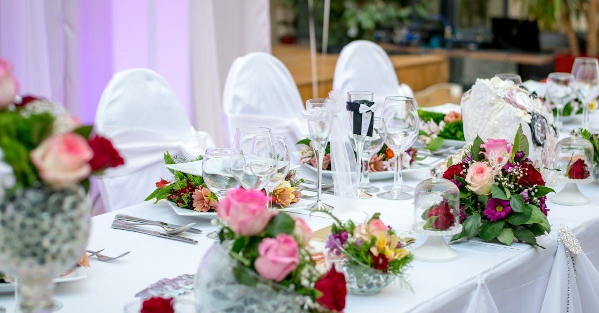 A long table set for a wedding reception with flowers on it.