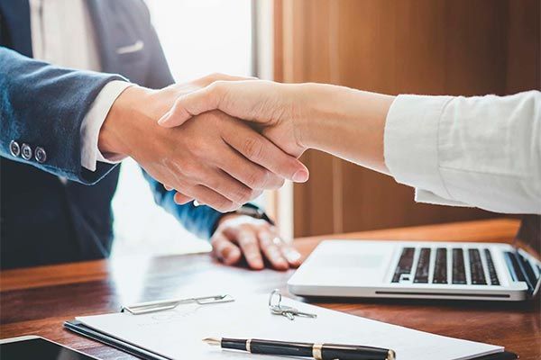 A man and a woman are shaking hands over a table.