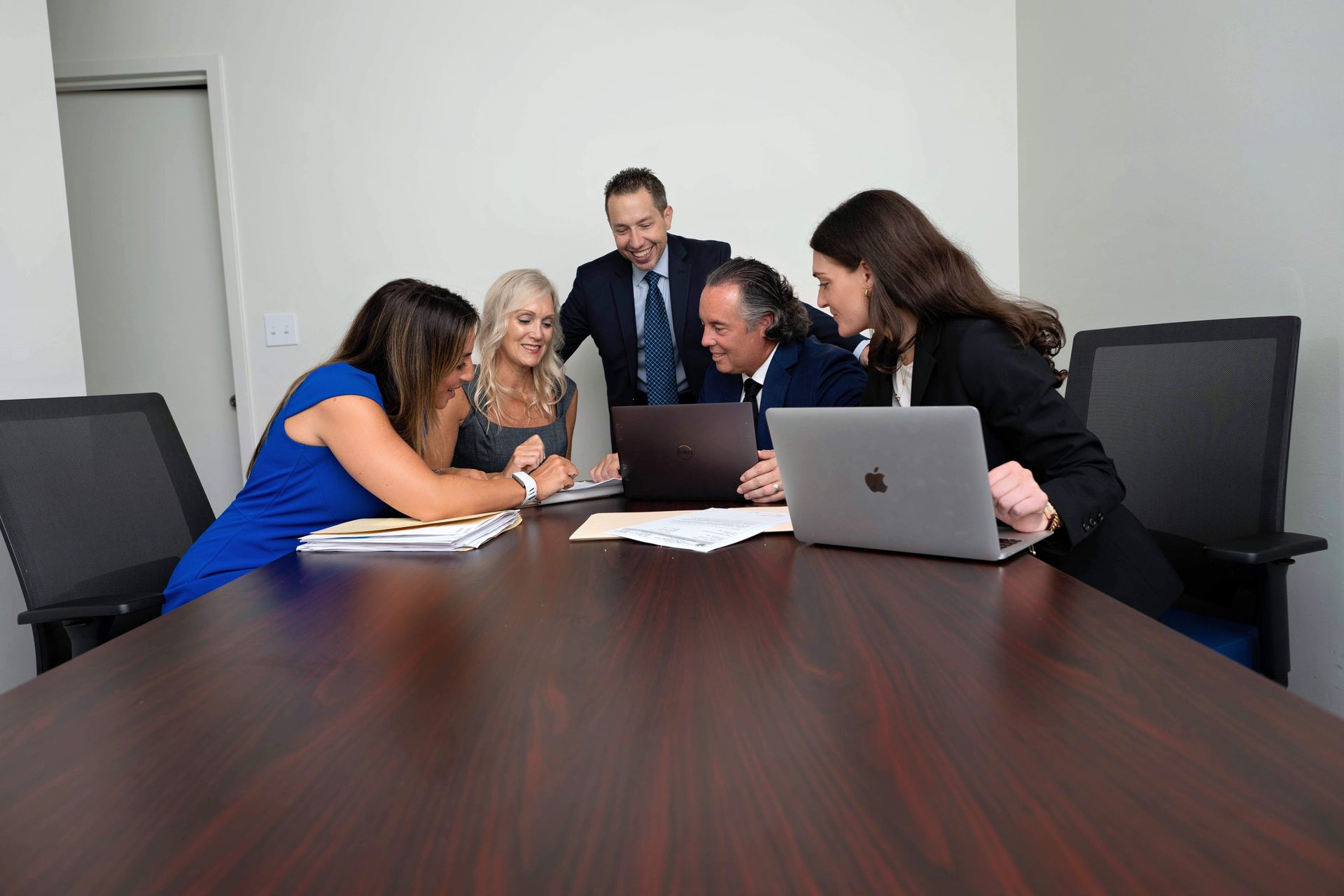 A group of people are sitting around a conference table with laptops.