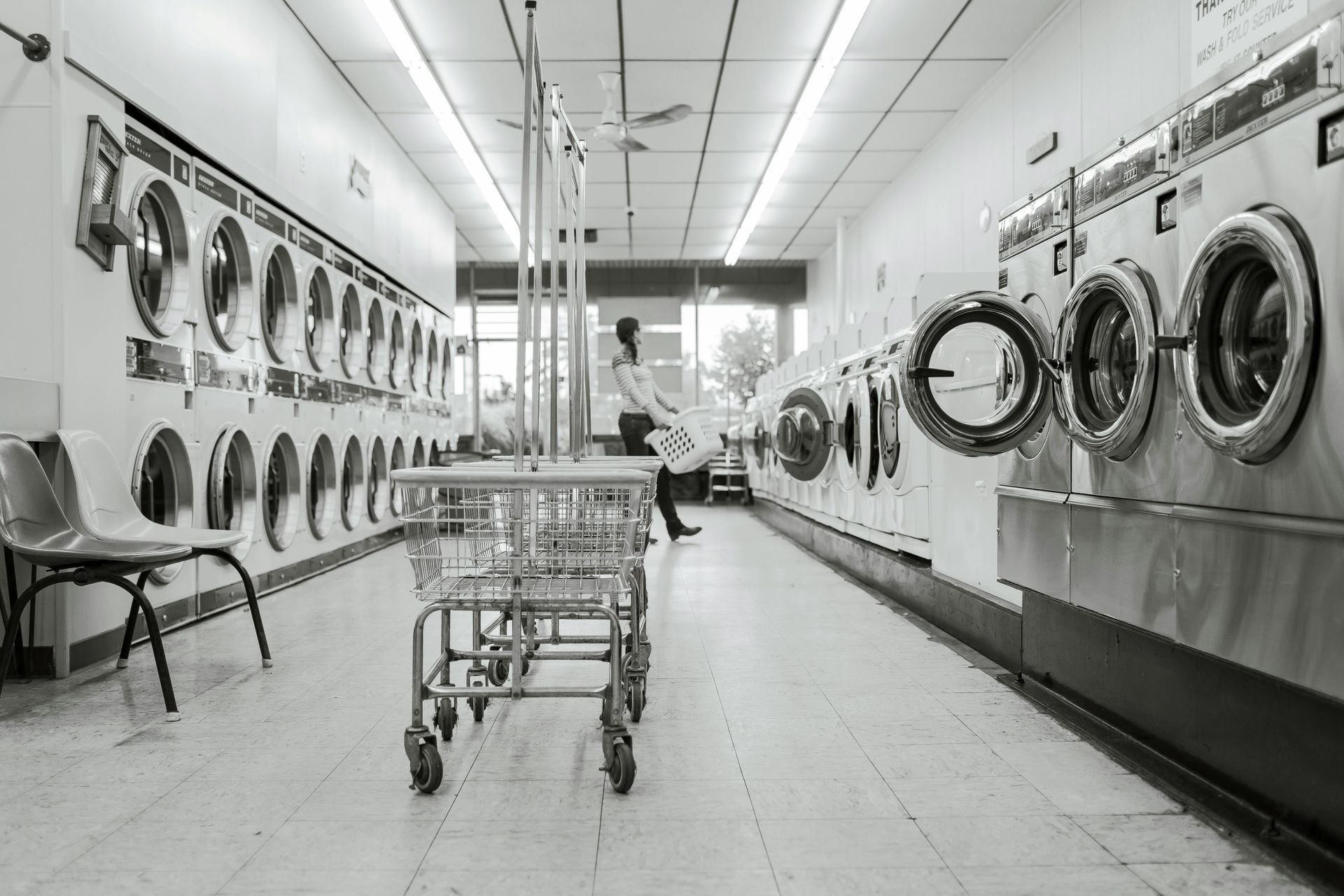 A black and white photo of a laundromat with lots of washing machines.