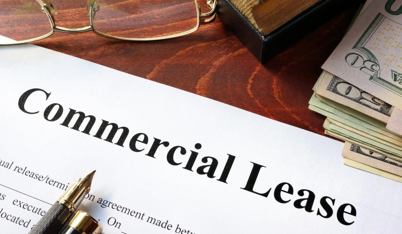 A stack of money is sitting on top of a commercial lease form