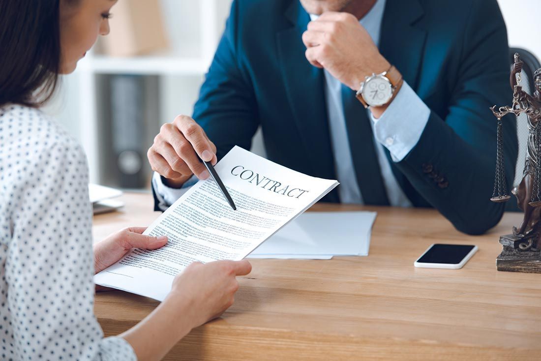 A man and a woman are sitting at a table looking at a contract.