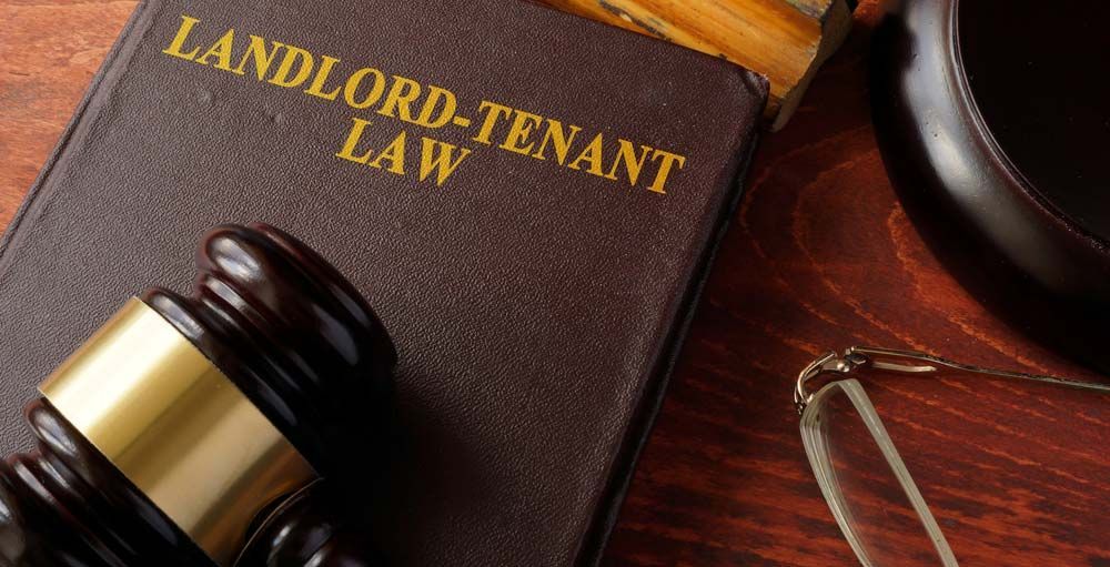 A wooden gavel is sitting on top of a book titled landlord-tenant law.