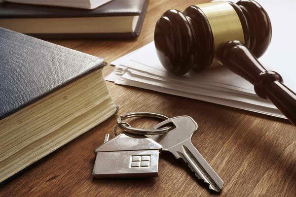 A judge 's gavel , keys , and a house keychain on a wooden table.