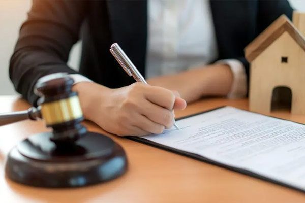 A woman is writing on a piece of paper next to a judge 's gavel.