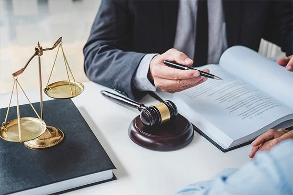 A man is sitting at a table with a book and a gavel.