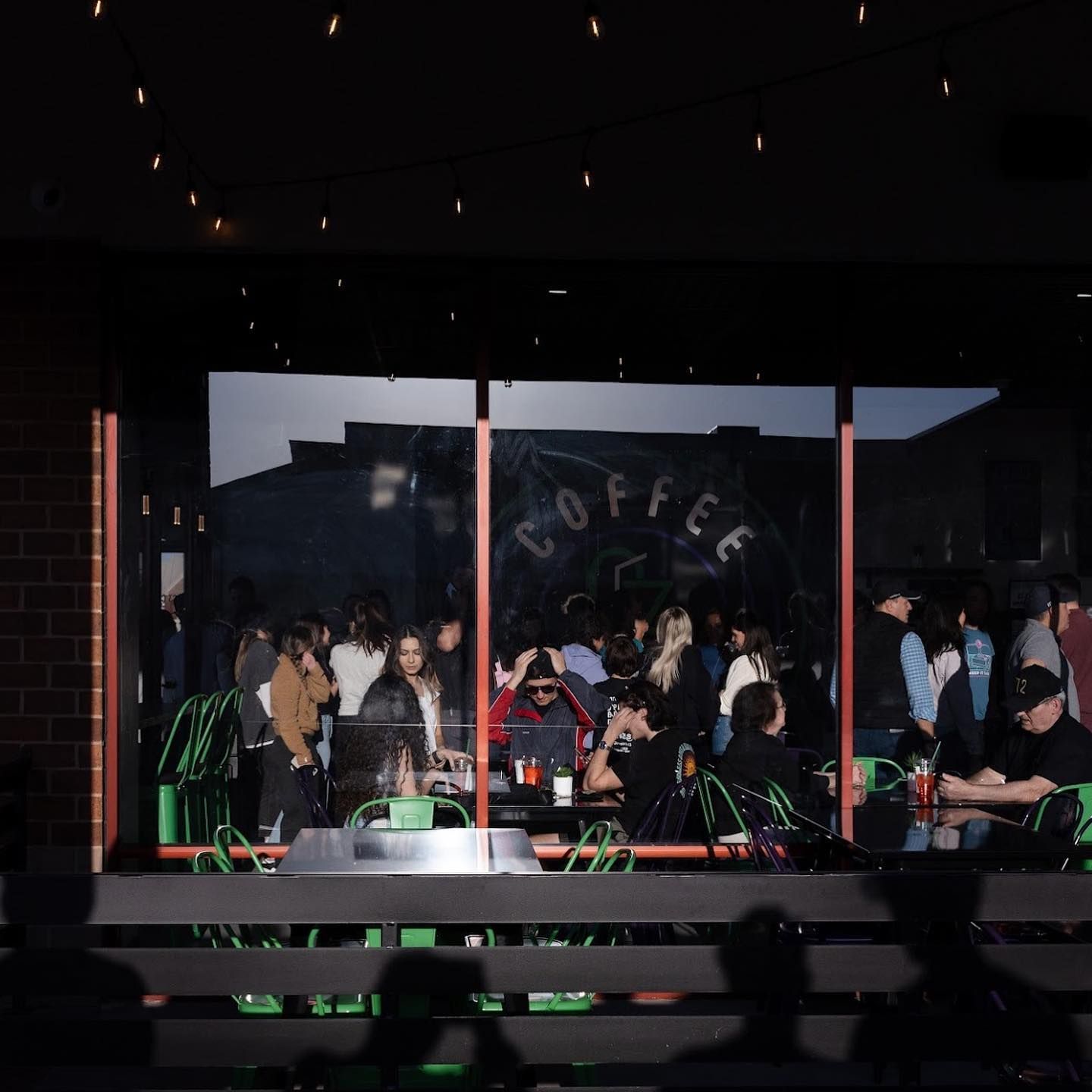 People gathered inside and outside a coffee shop with 