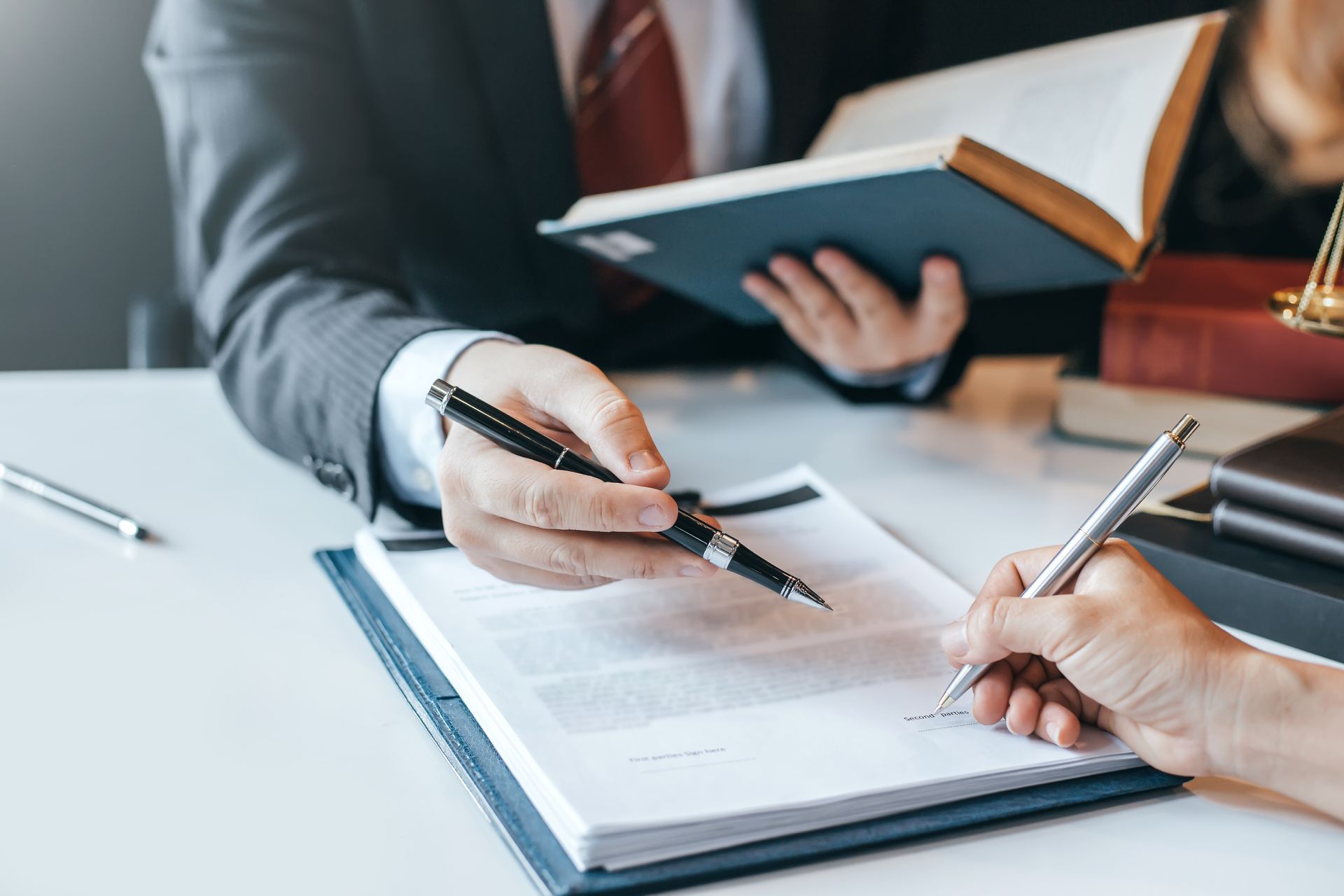 A man and a woman are sitting at a table signing a document.