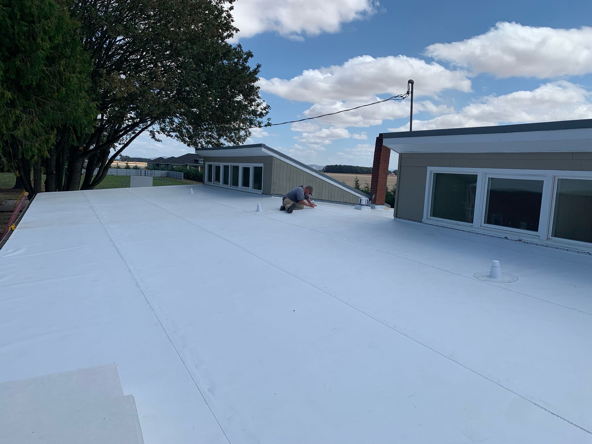 A man is laying on top of a white roof.