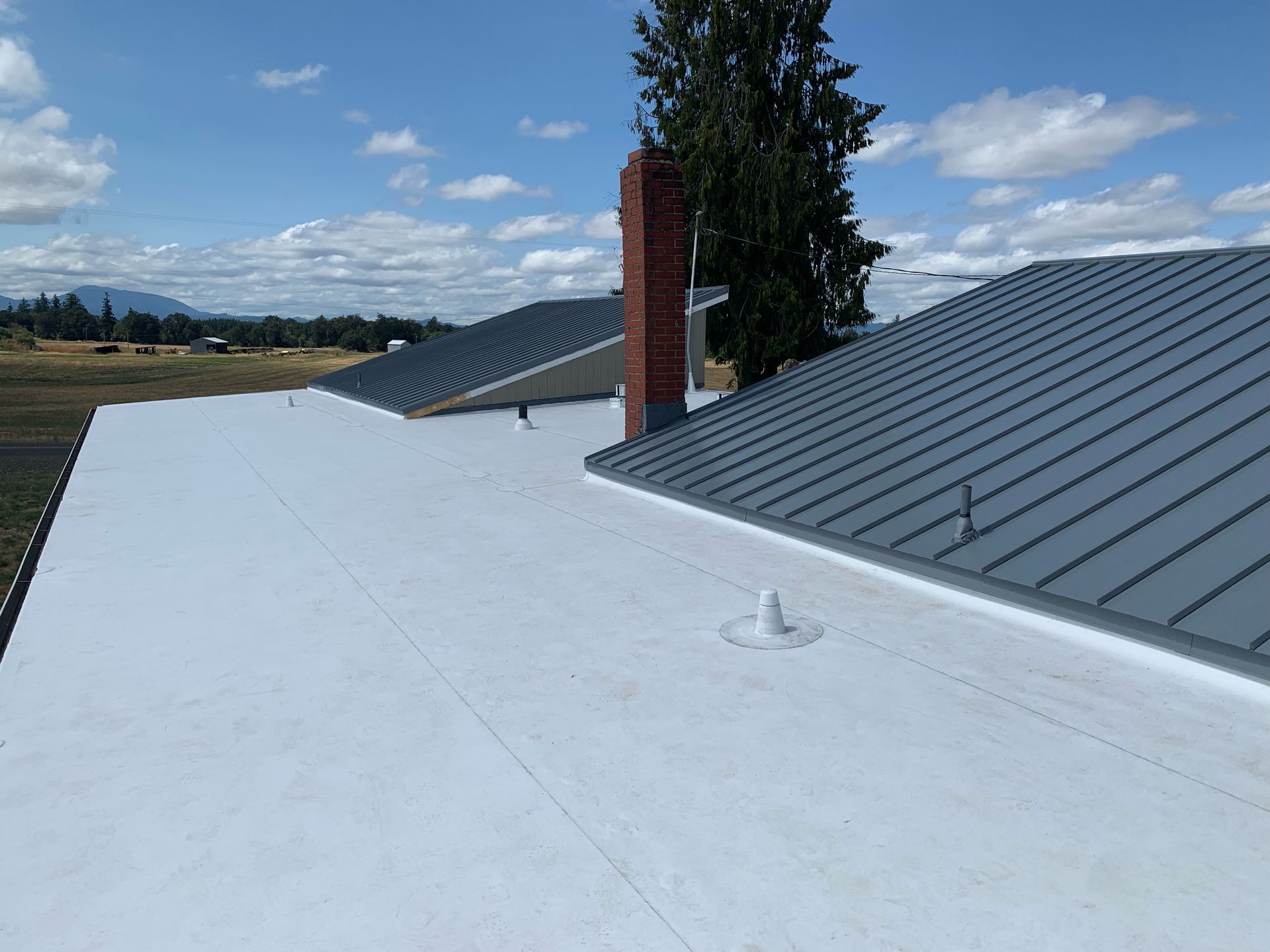 A white roof with a gray roof and a chimney on top of it.