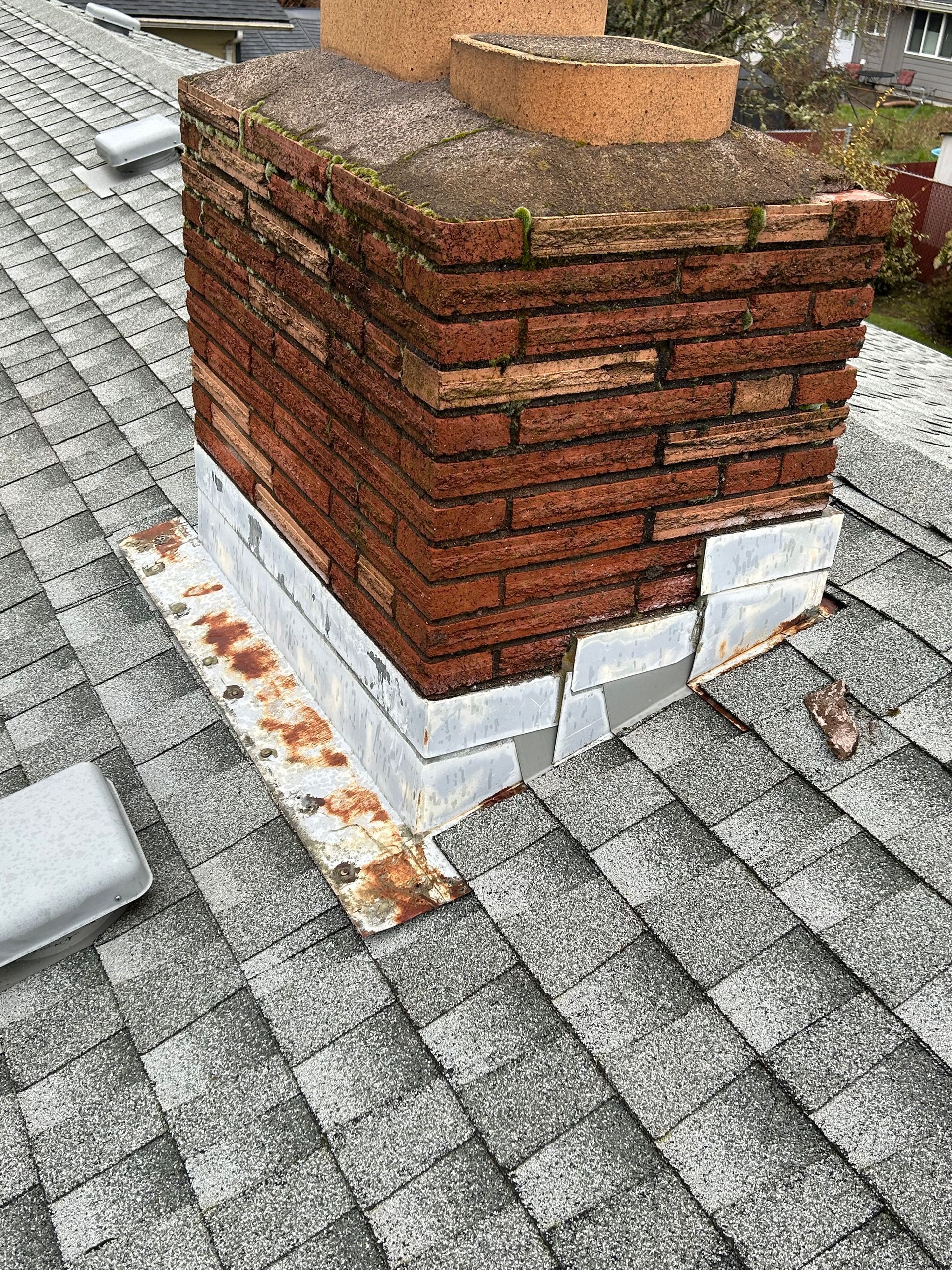 A brick chimney is sitting on top of a roof.