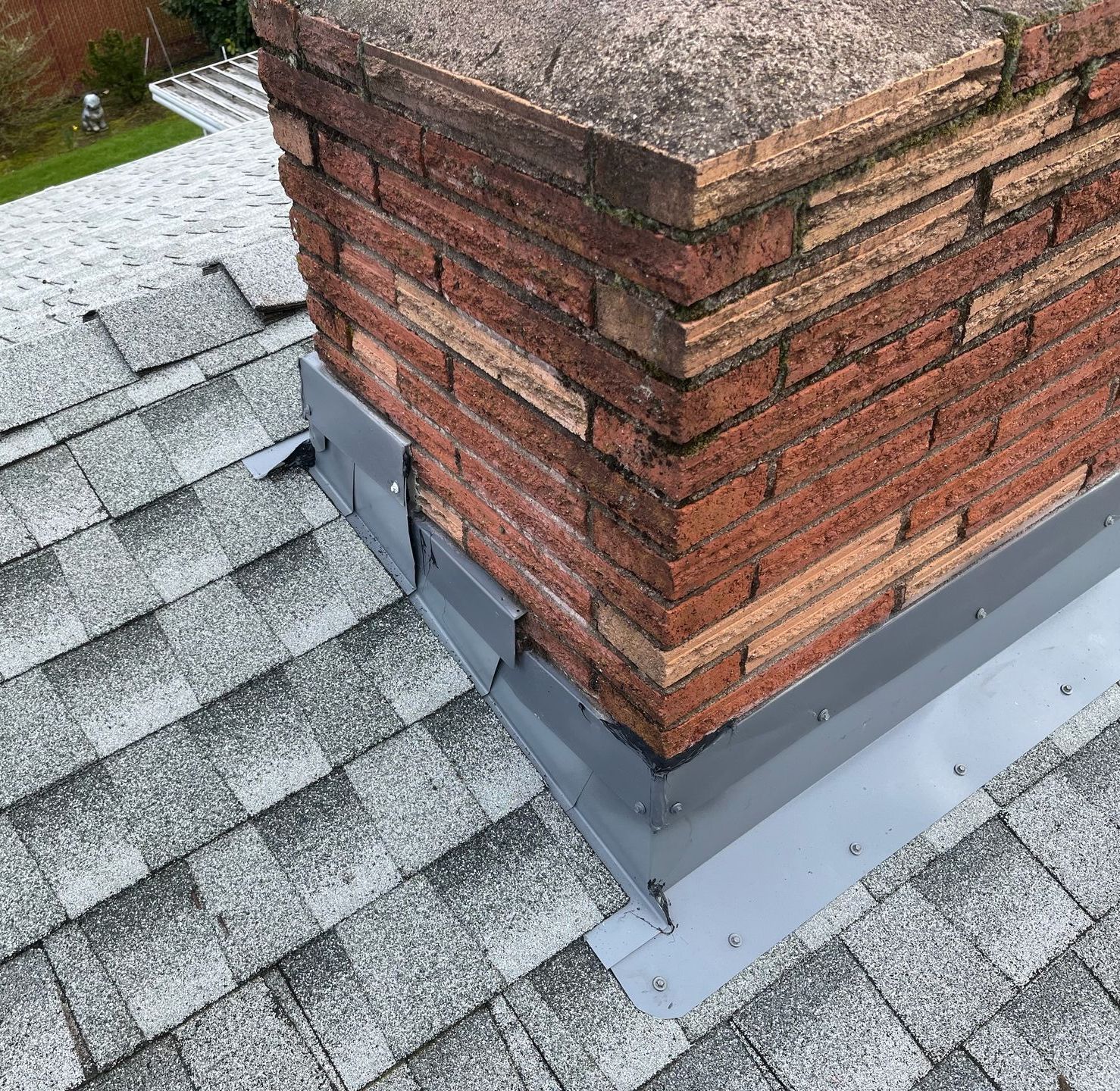 A brick chimney is sitting on top of a roof.
