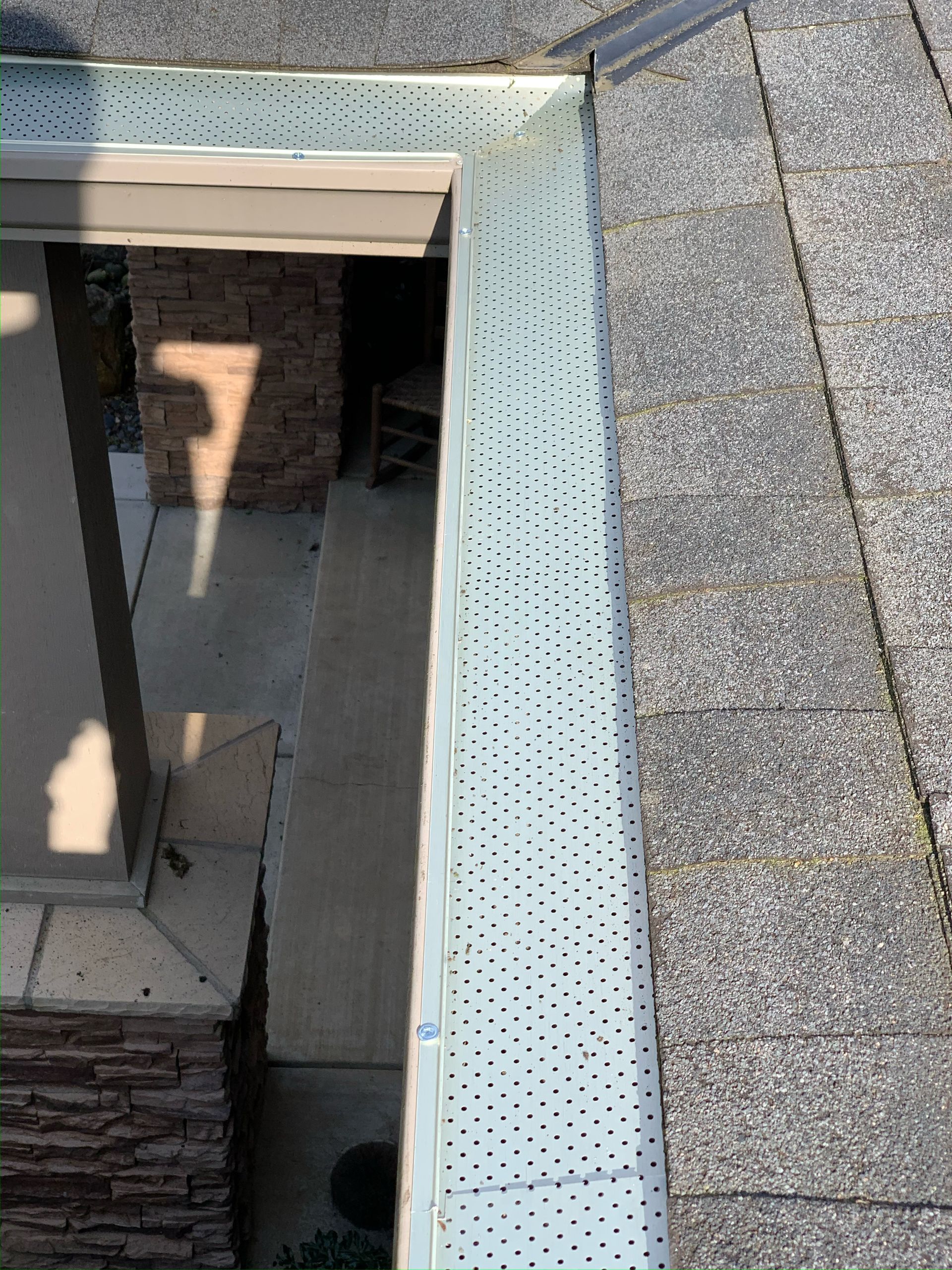 A close up of a gutter on a roof next to a window.
