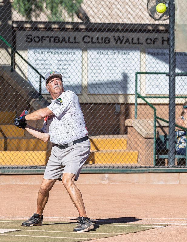 Baseball glove with ball on green grass, with blurred baseballs in the background.