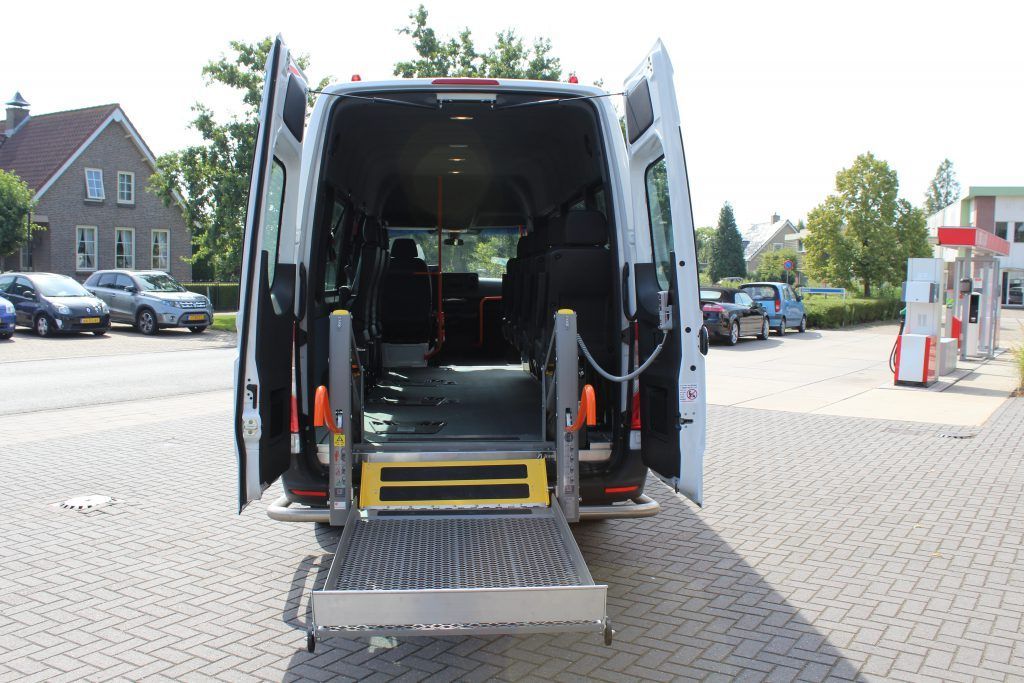 een wit busje van taxi amstelveen met de deuren open en een oprit achterin