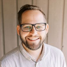 A man with glasses and a beard is smiling for the camera.