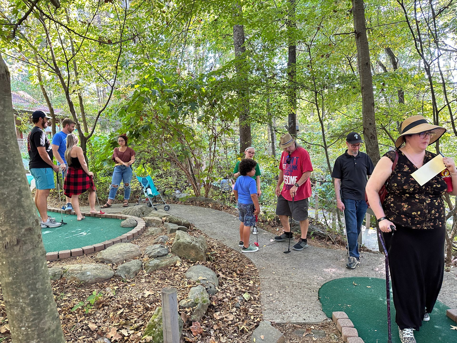 A group of people are playing mini golf in the woods.