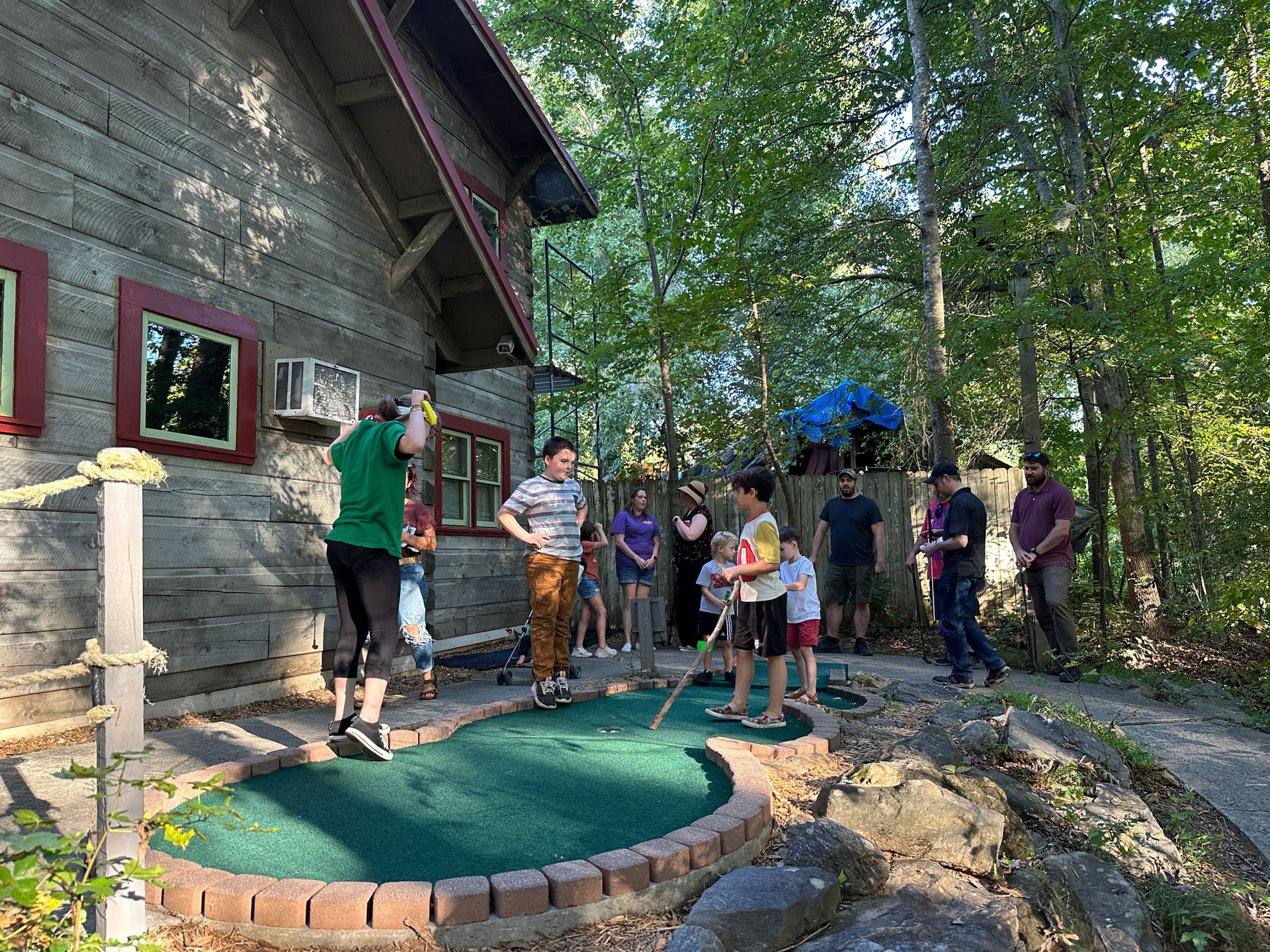 A group of people are playing a game of mini golf in front of a house.