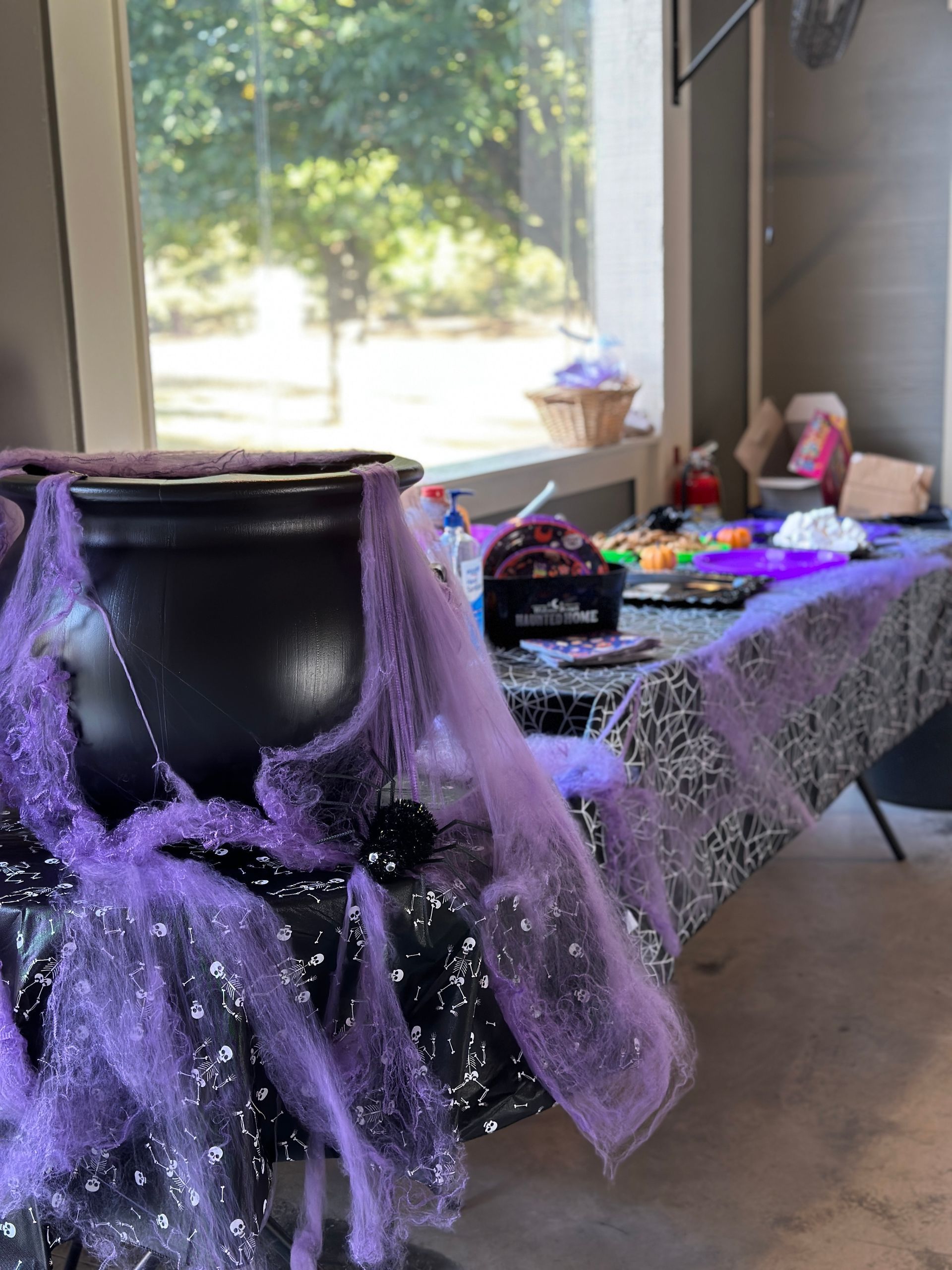 A table decorated for halloween with a cauldron and spider webs.
