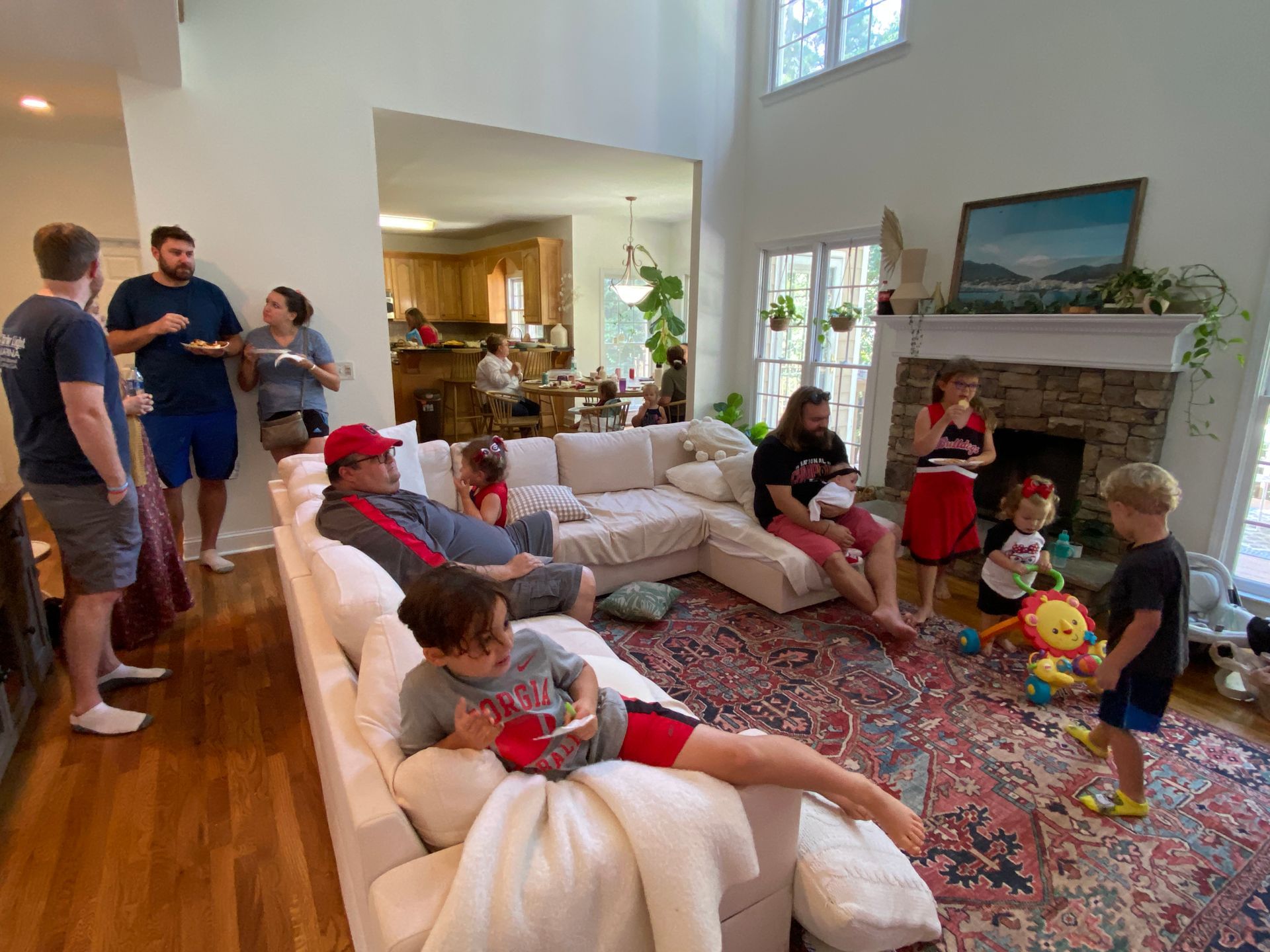 A group of people are sitting on a couch in a living room watching a football game