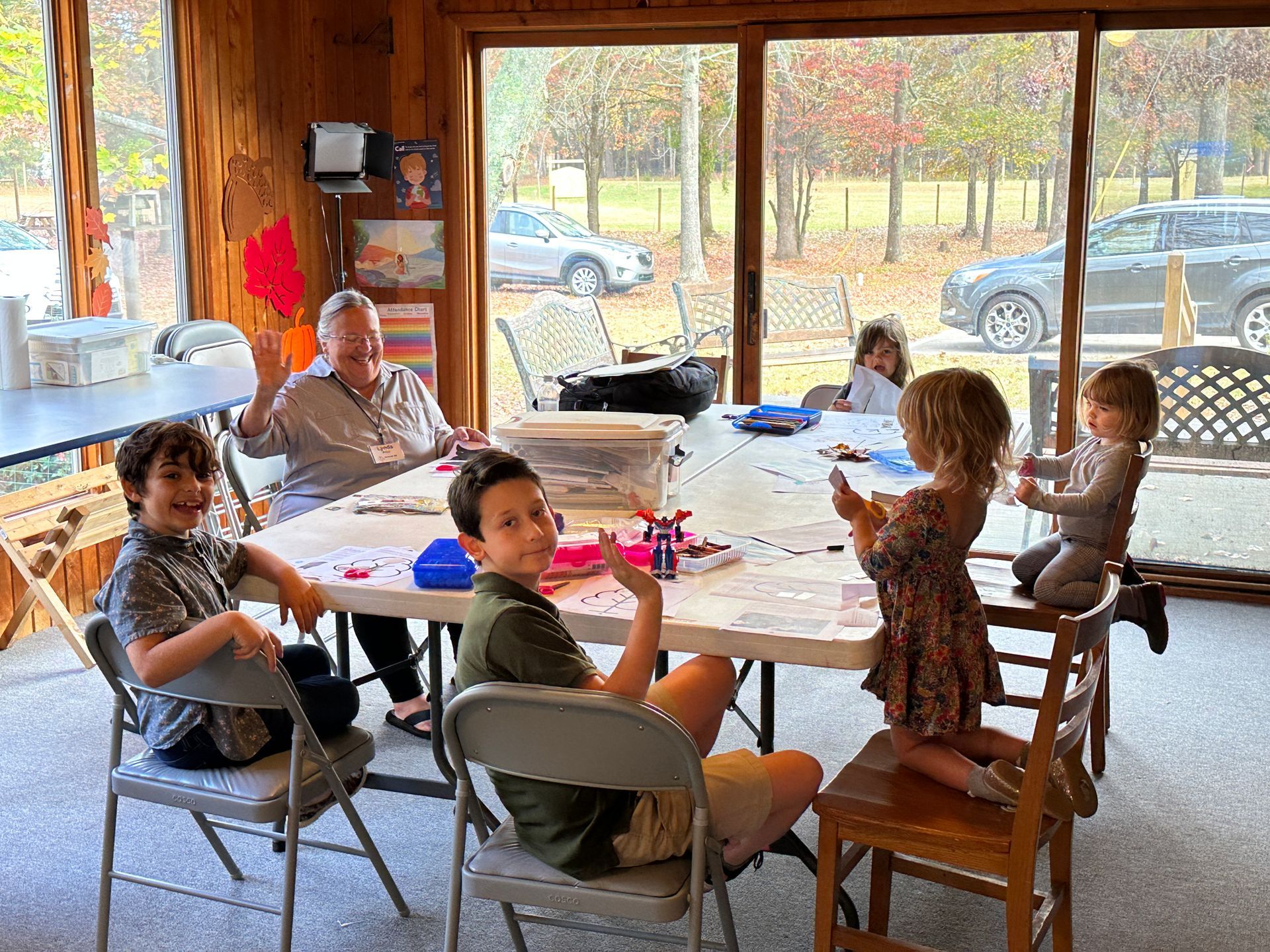 A group of children are sitting around a table in a room.
