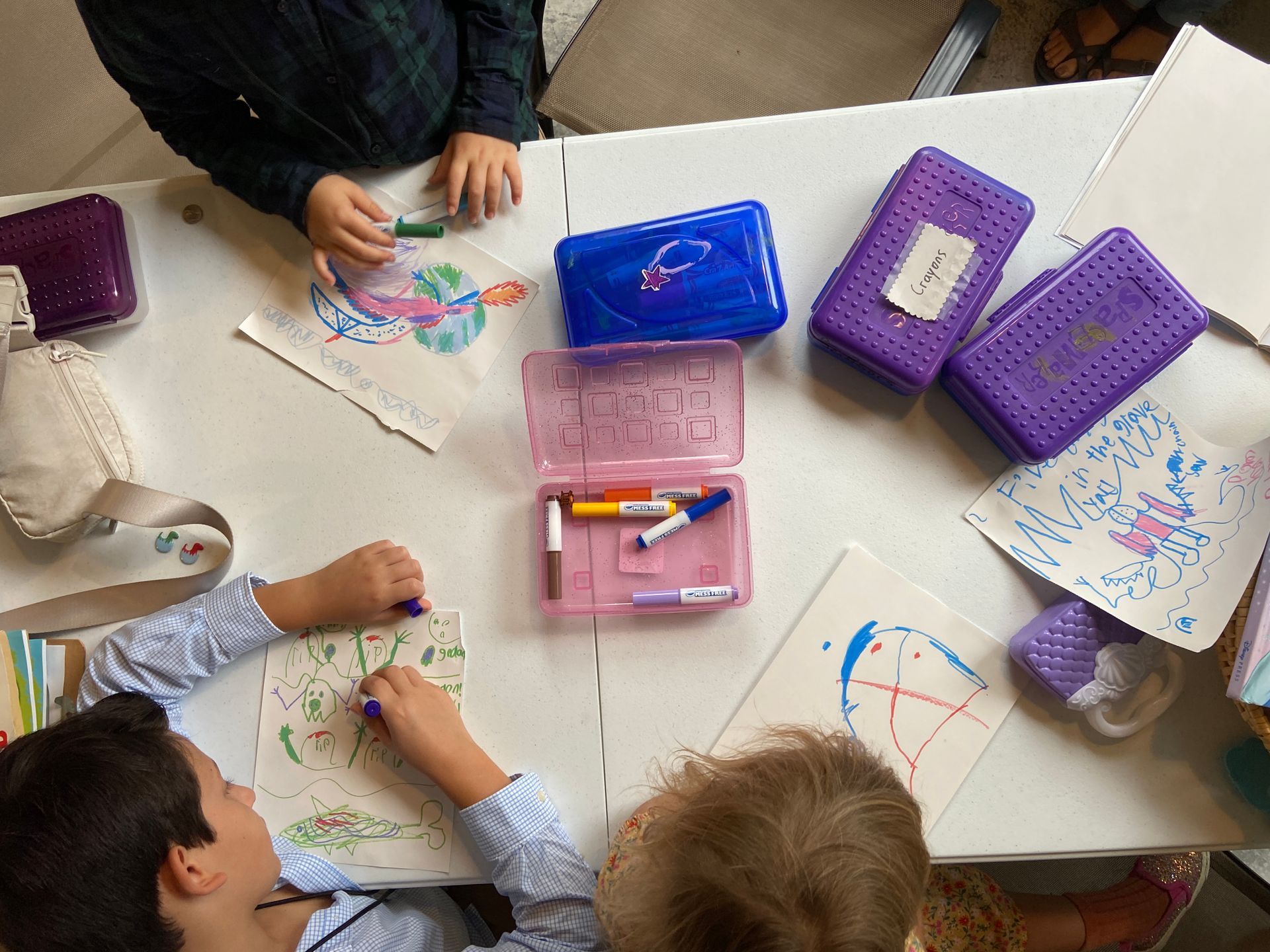 A group of children are sitting at a table drawing with markers.