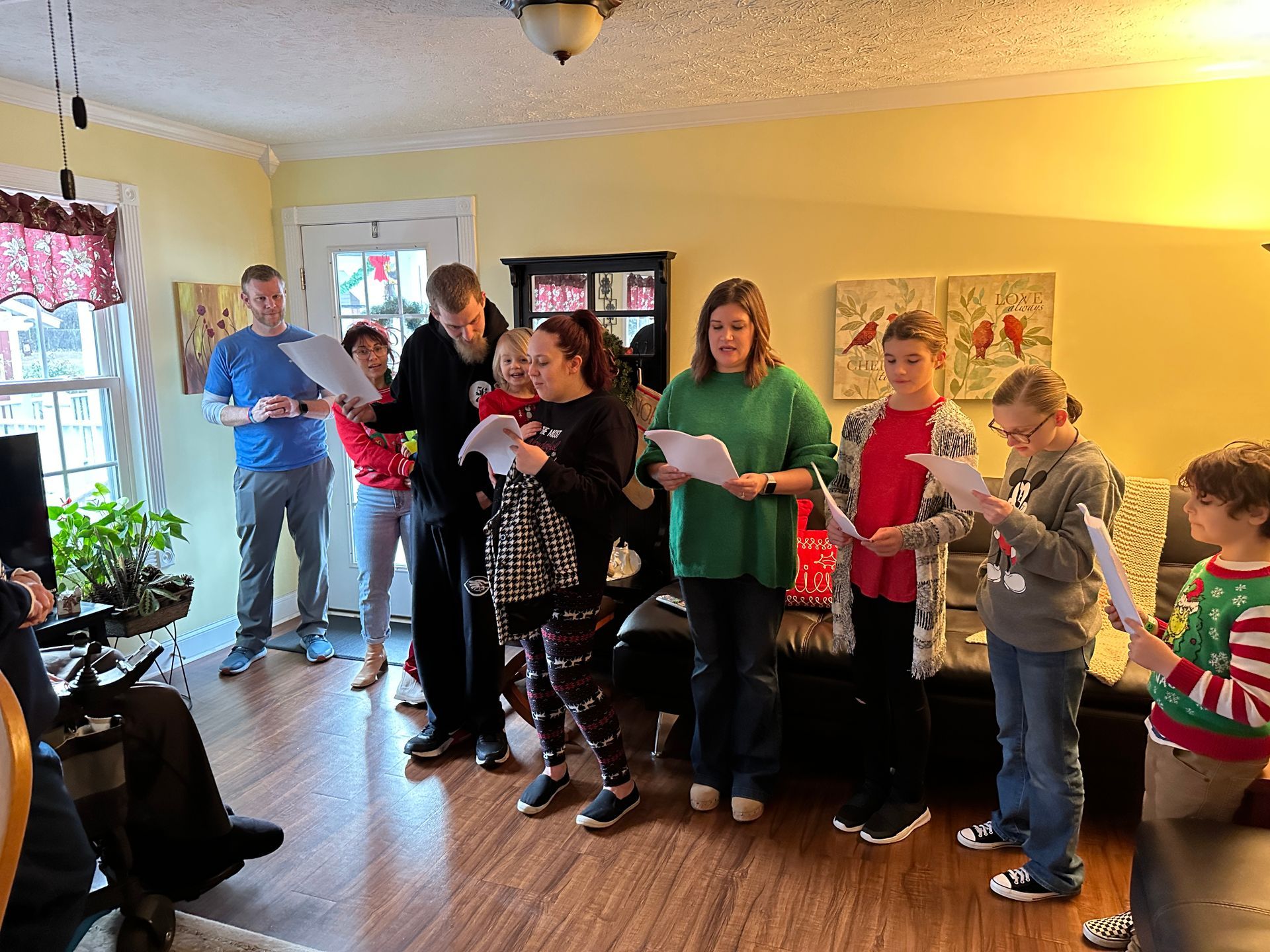 A group of people are singing christmas carols in a living room.