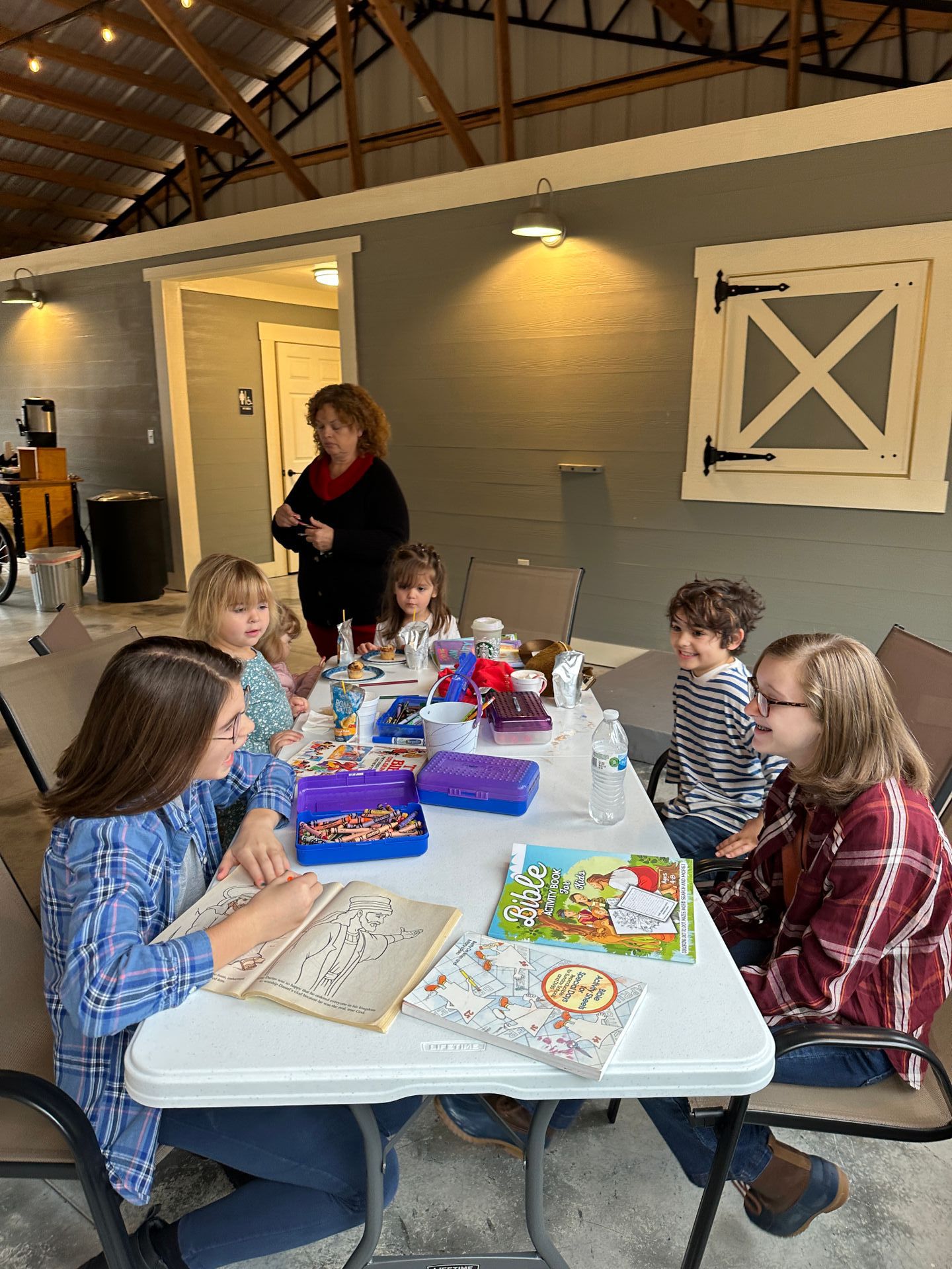 A group of children are sitting at a table in a pavilion