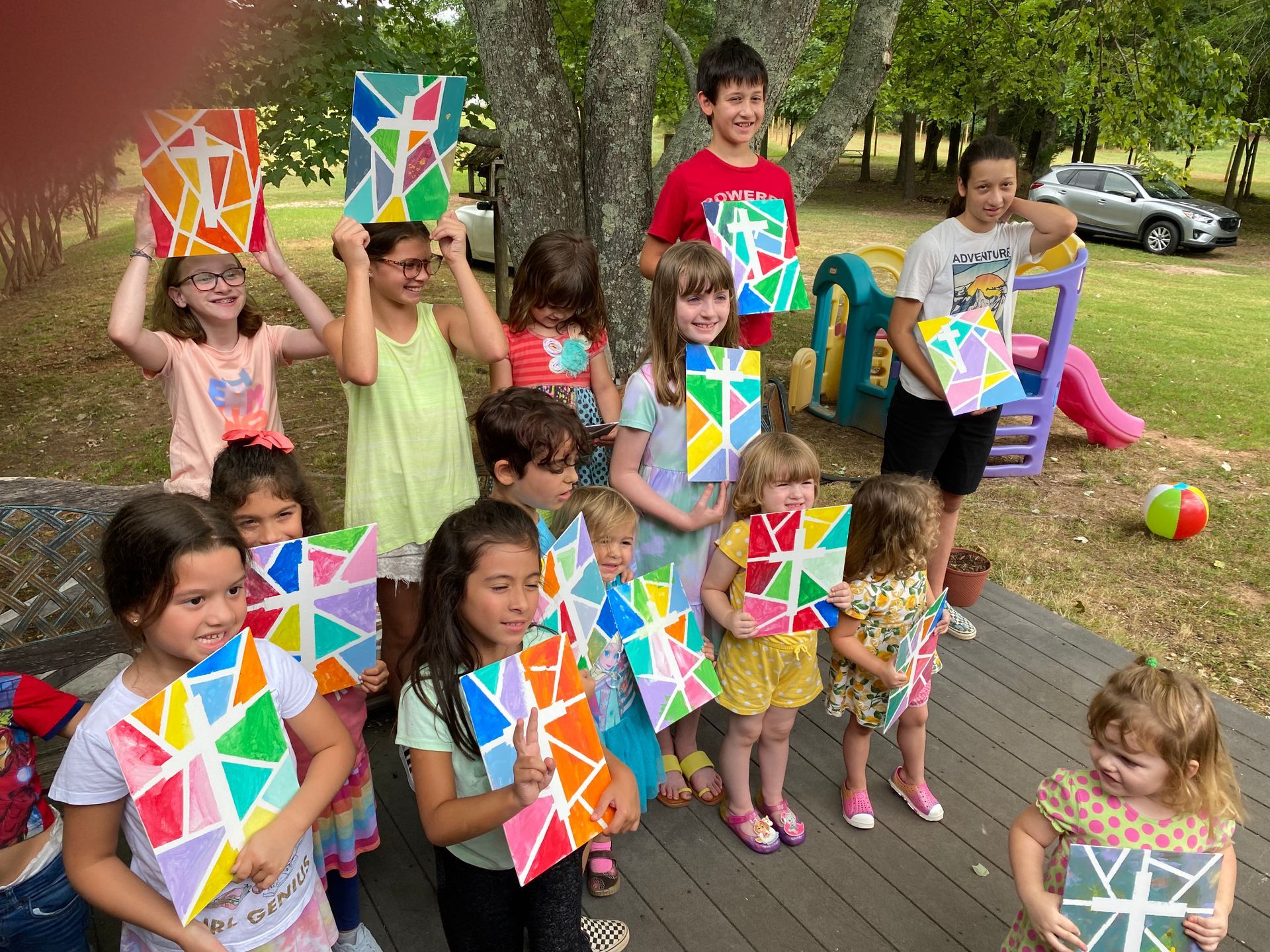A group of children are standing next to each other holding painted stained glass windows