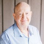 A bald man in a blue shirt is smiling for the camera.